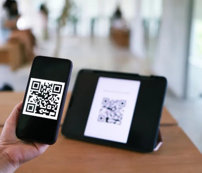 شخص يقوم بمسح رمز الاستجابة السريعة على جهاز لوحي باستخدام iPhone 